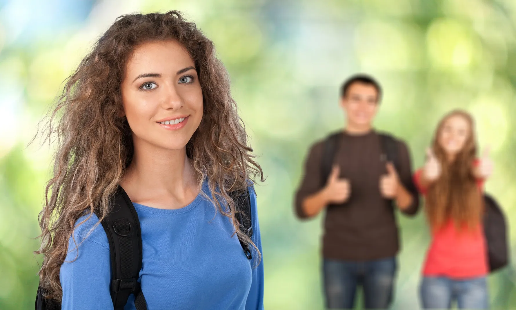 A smiling young woman in the foreground with students behind her