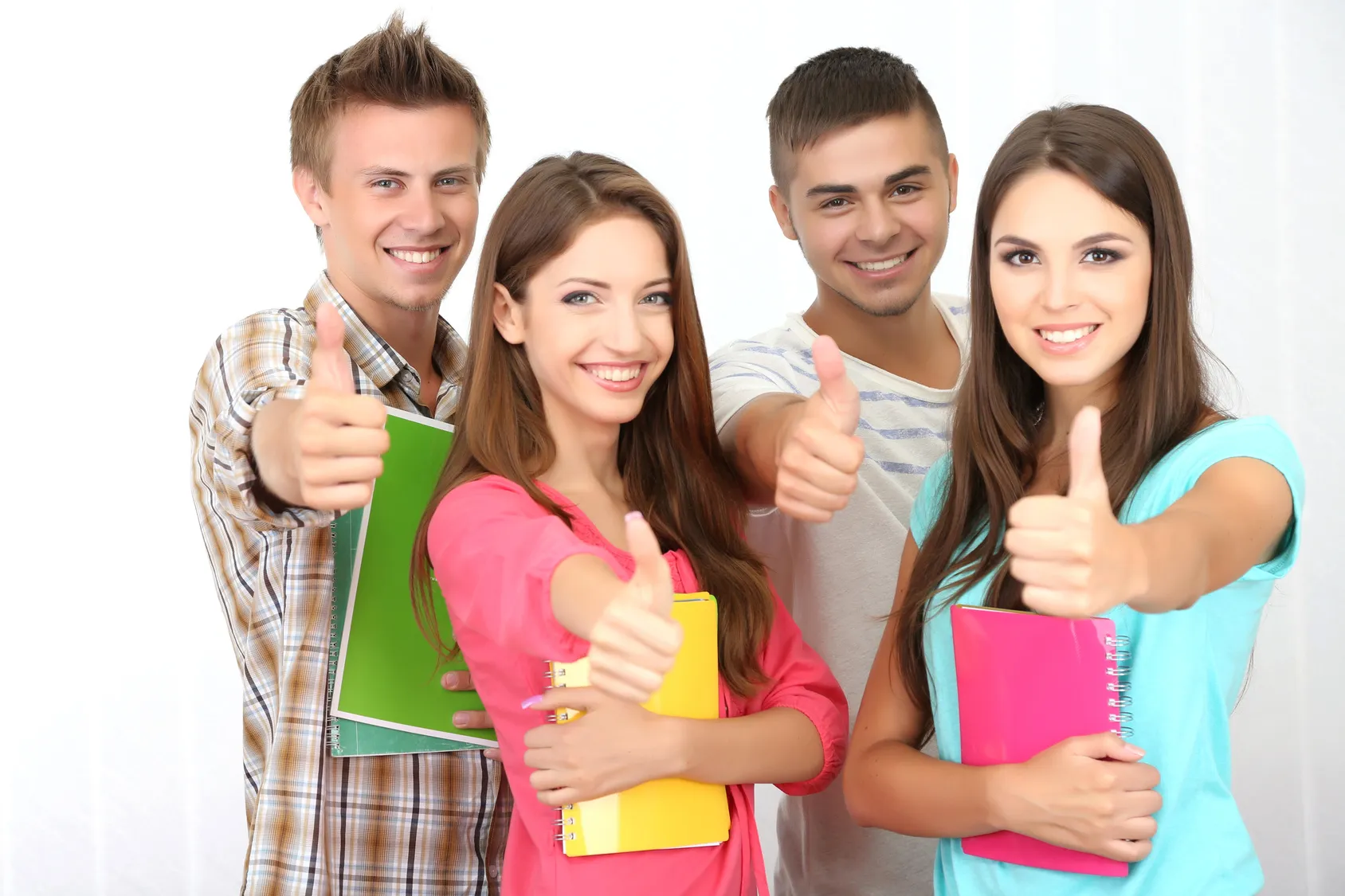 Group of smiling students giving thumbs up while holding notebooks