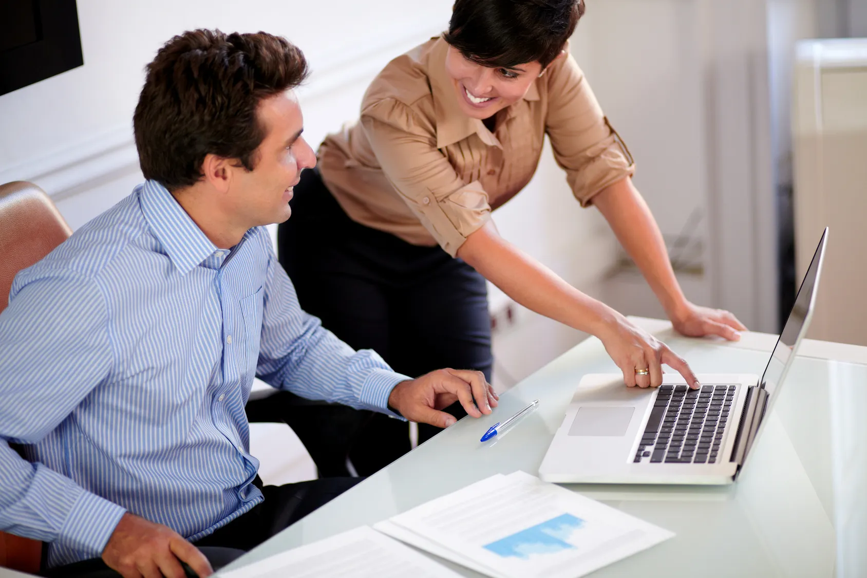 Two colleagues reviewing a chart together on a laptop