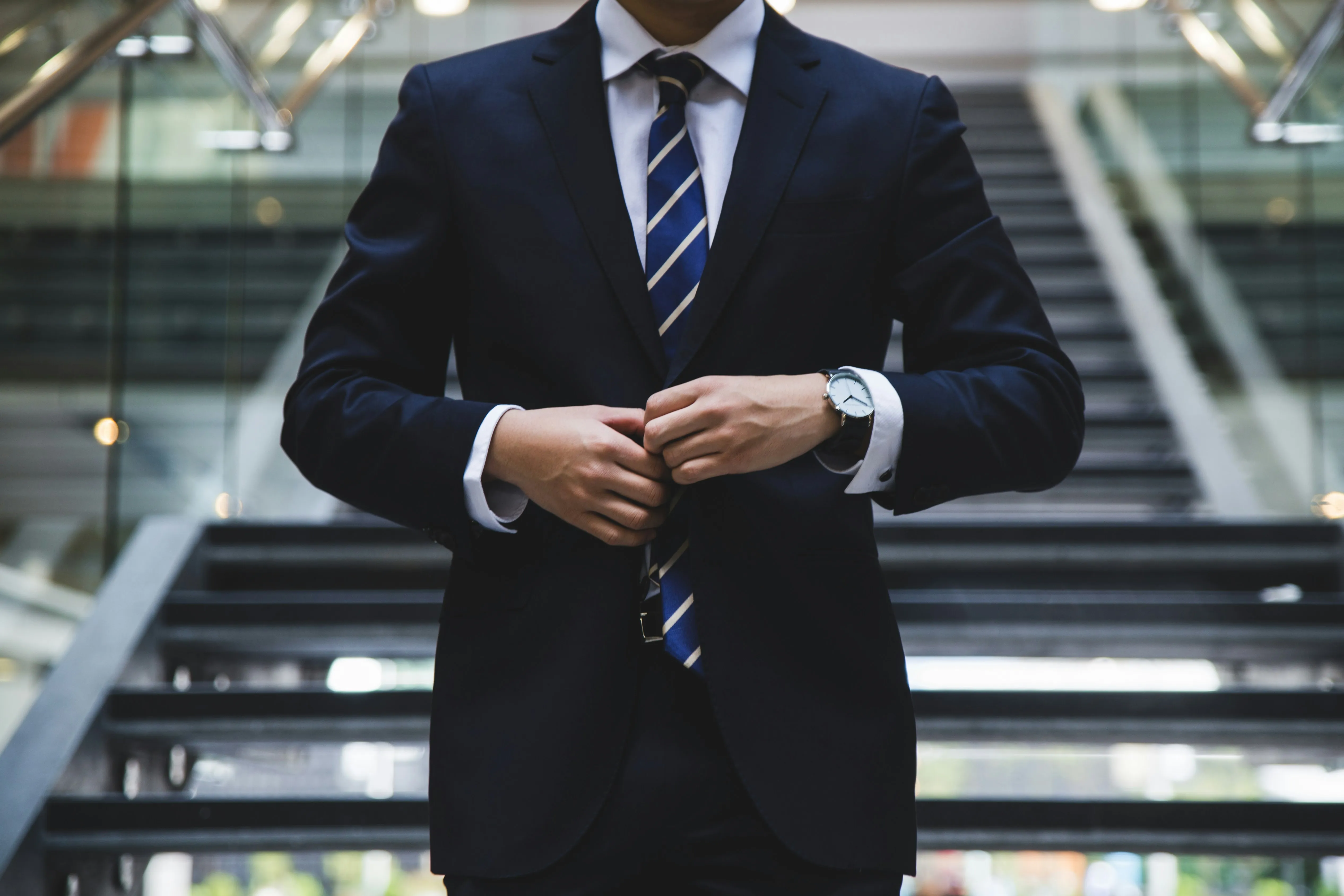 A professional in a suit checking a watch on a staircase