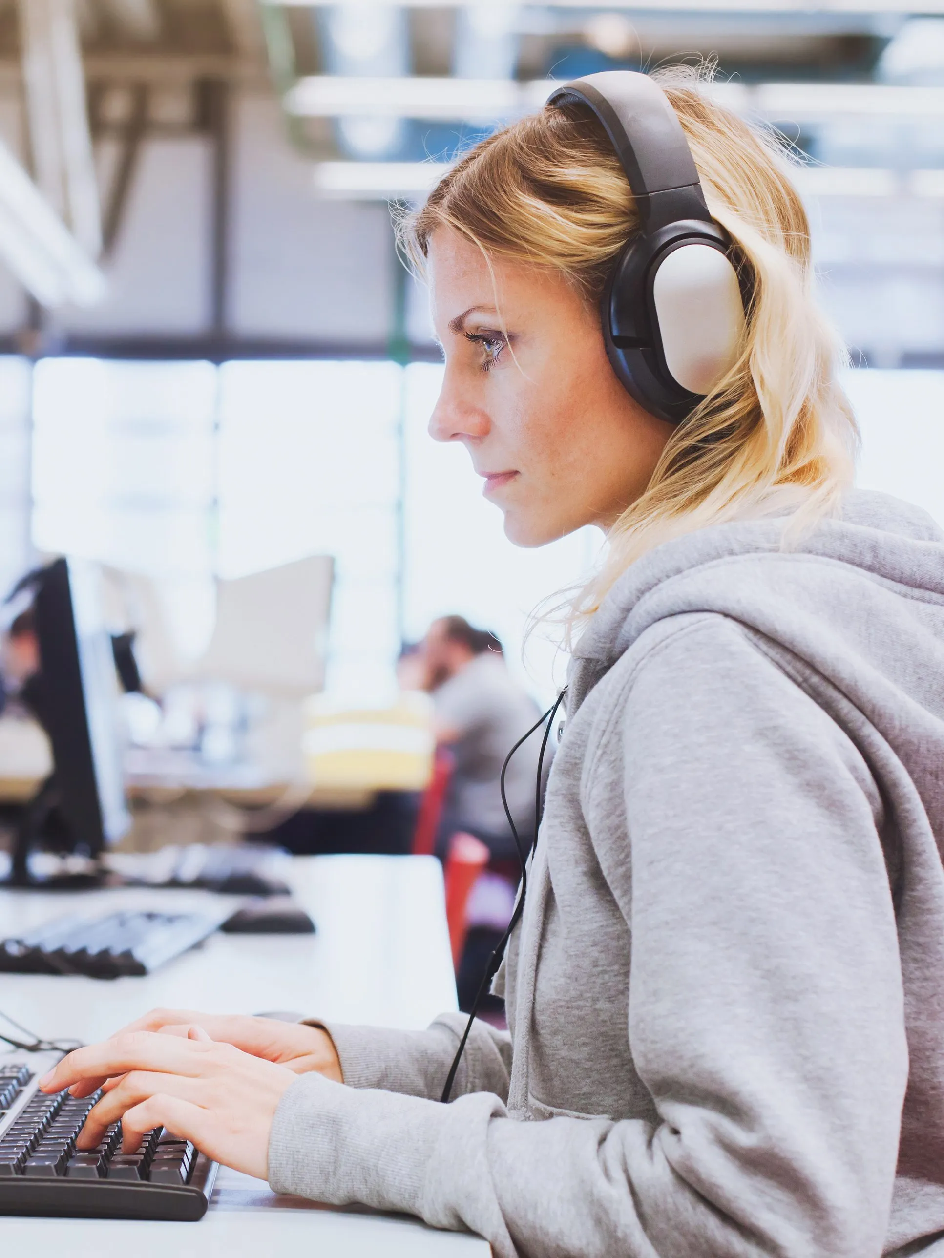 A woman wearing headphones and working at a computer