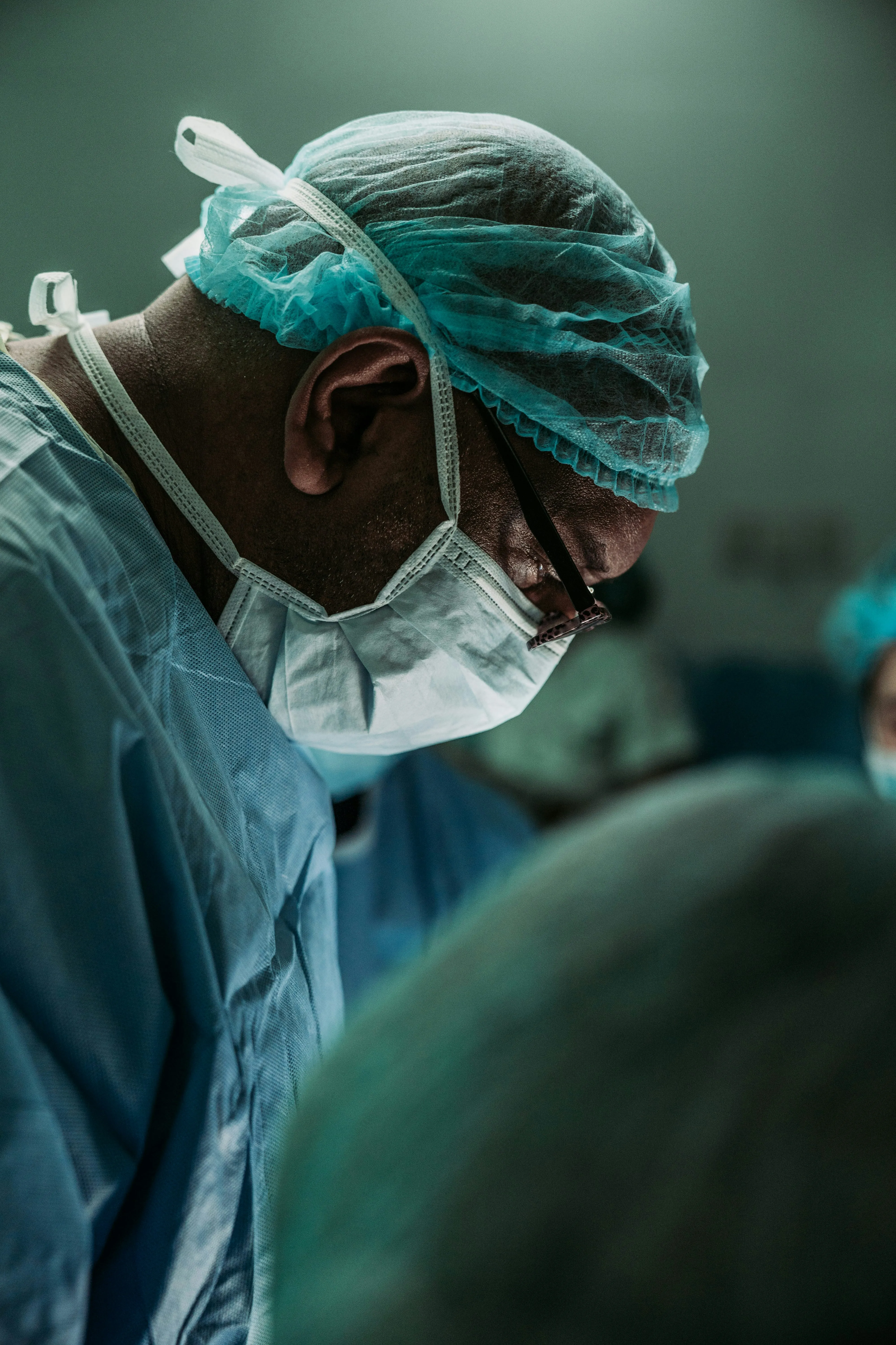 A surgical team member in a theatre cap and mask