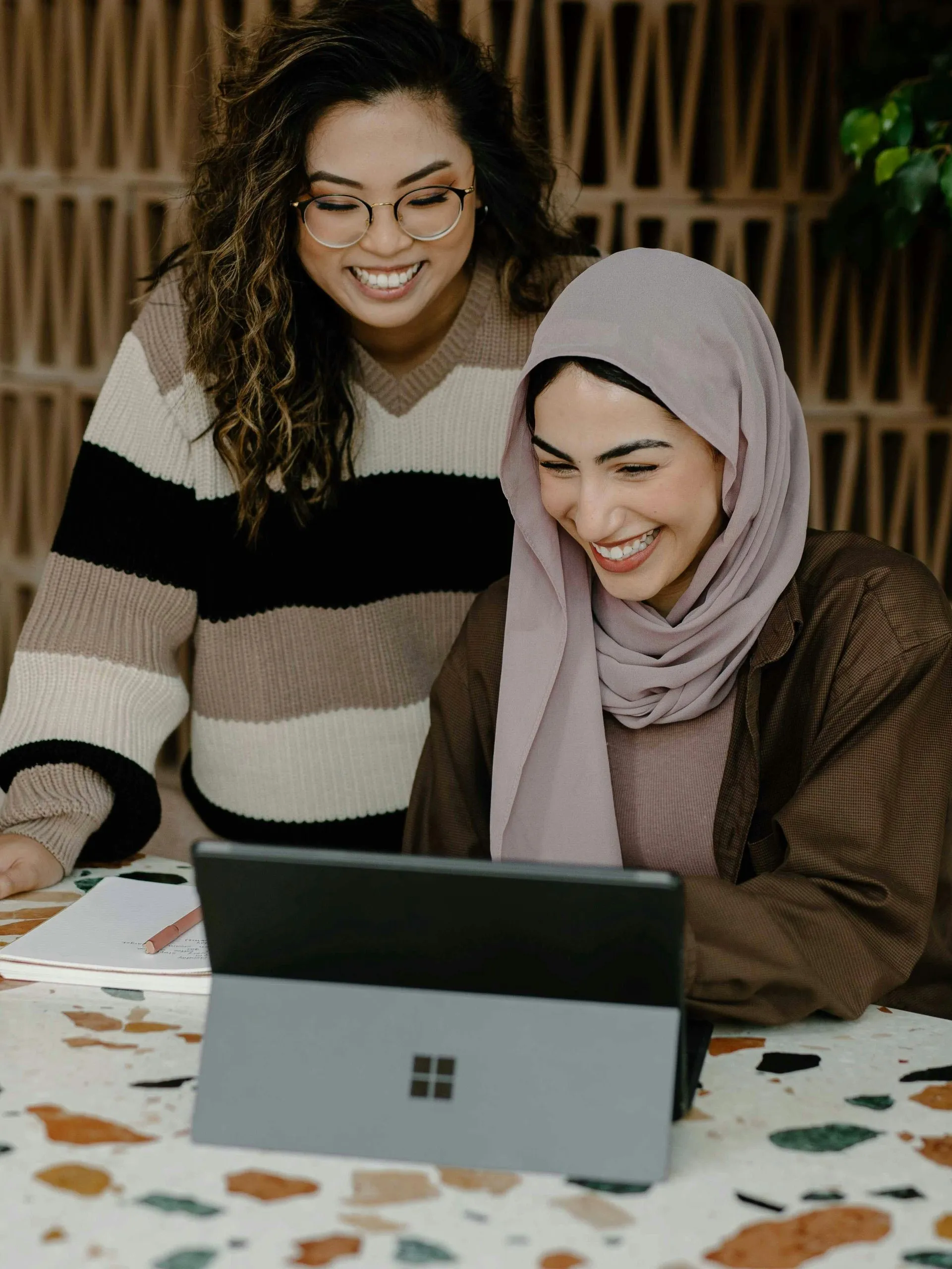 Two colleagues smiling at a tablet on a desk