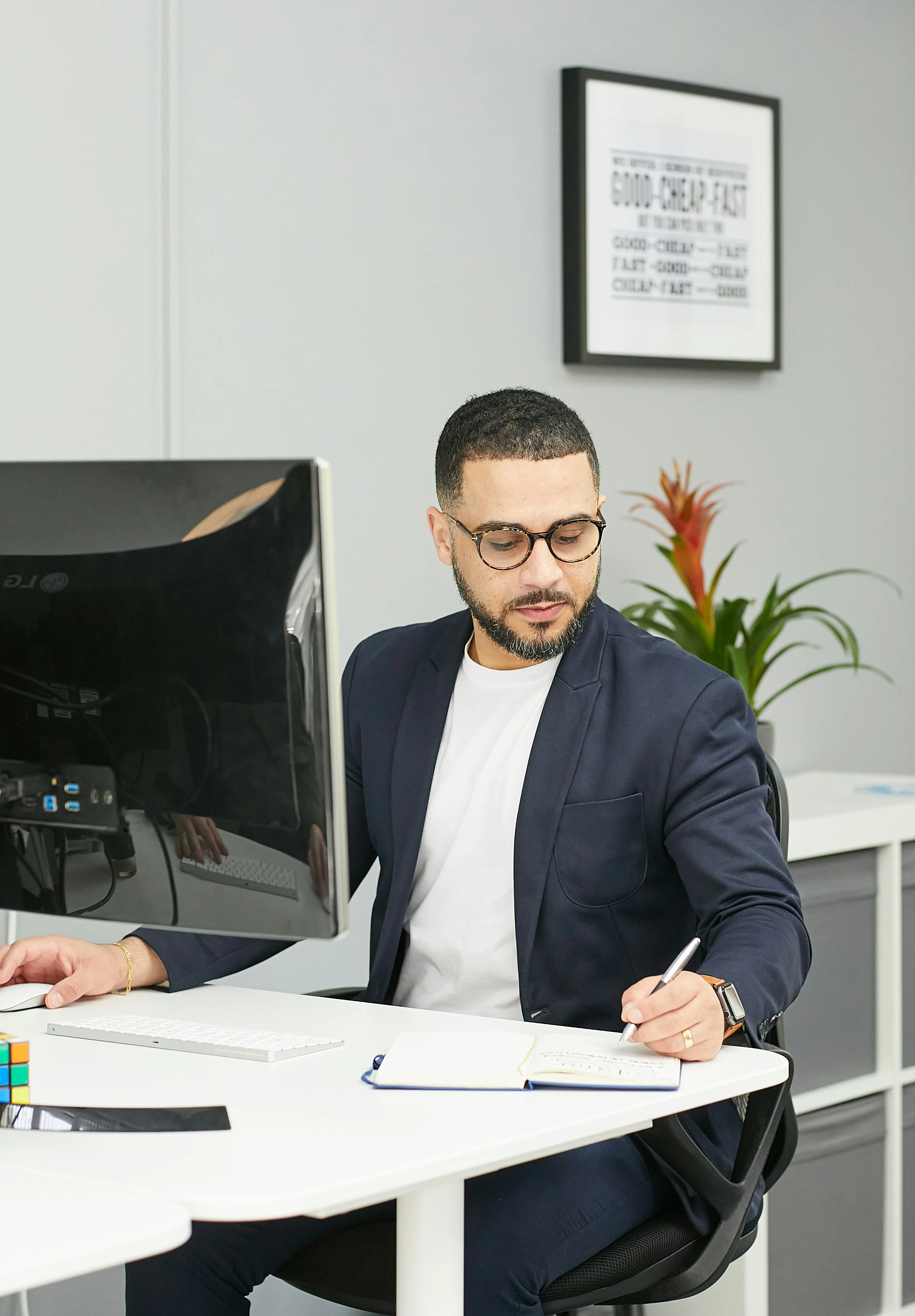 A man in a navy blazer working at a desk with a computer